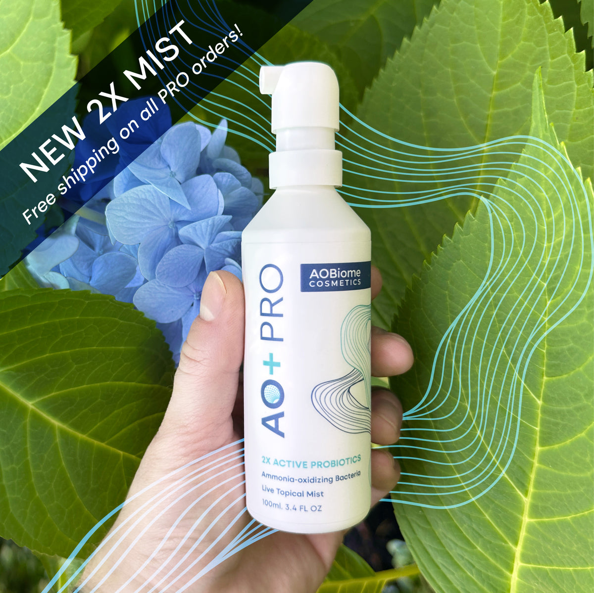 Hand holding a bottle of AO+ PRO against a background of leaves and blue flowers