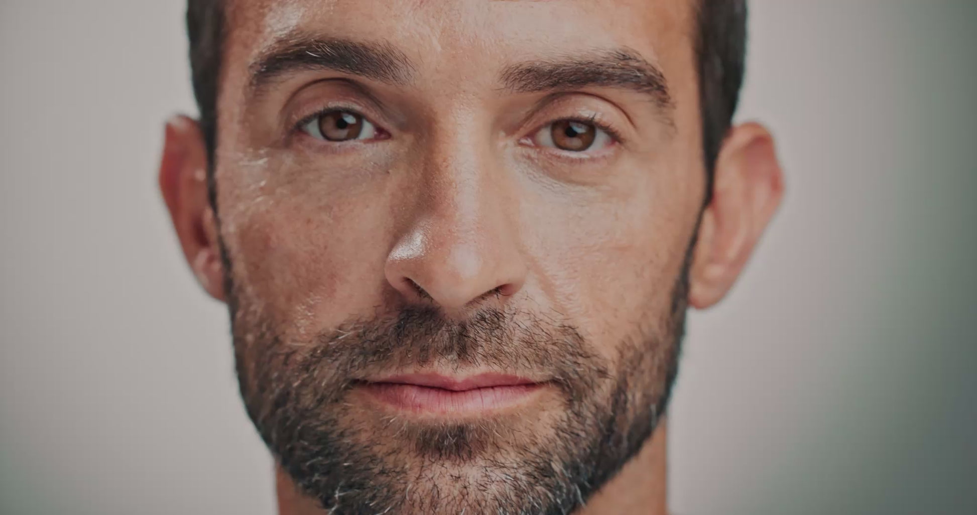 Close-up of a man's face as he closes his eyes and a spray of mist hits each side of his face before he opens his eyes and smiles.